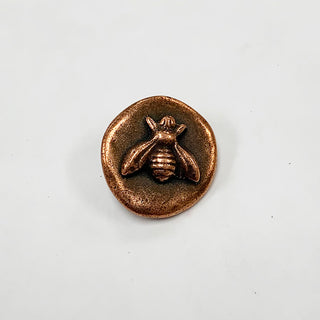 Small round copper button with raised bee embossed.