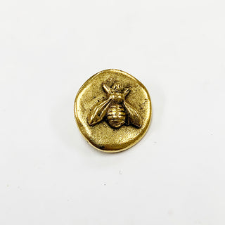 Small round gold button with raised bee embossed.