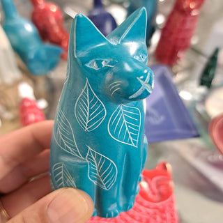 Fingers holding a blue cat soapstone carving