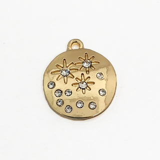 Front side of  a round gold plated charm with 12  clear crystals and star engravings.