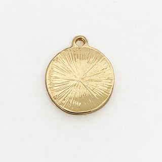 Back side of  a round gold plated charm with textured surface.