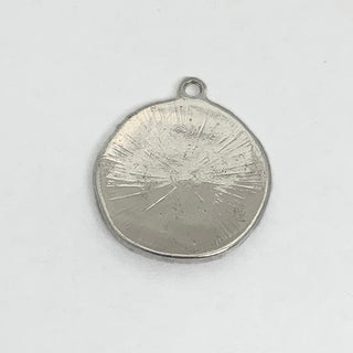 Back of silver plated round charm with engraved starburst design.