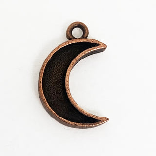 Front side of textured copper tone crescent shaped charm with lip.