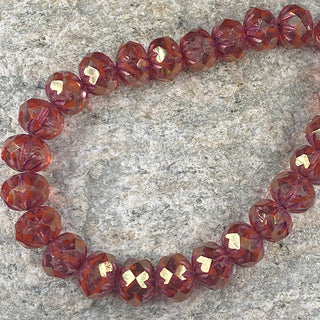 Strand of faceted Czech glass ruby gold with pink cruller beads.