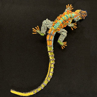 Lizard pin covered in beads, sequins, and embroidery.