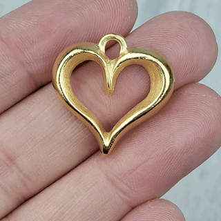 large gold colored hard shaped charm on a person's hand