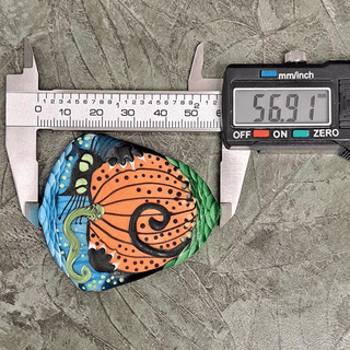 Lampwork glass bead of black cat with pumpkin with calipers measuring its size