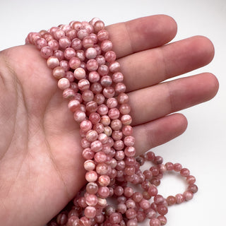 Rhodochrosite 5.5mm Round 15in Strand in hand
