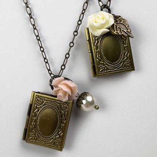 Two locked necklaces with vintage-style book pendants and floral elements on a light background
