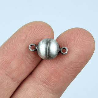 silver magnet on fingers white background