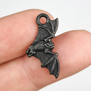 Tierracast Bat Charm Black 12x23mm on a person's fingers