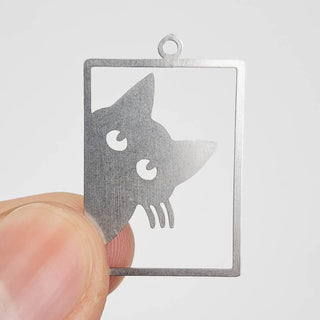 stainless steel charm that looks like a cat peering out of a window frame