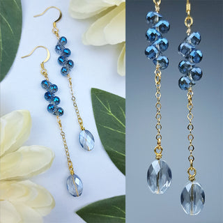 blue crystal earrings on gold chain with a floral background