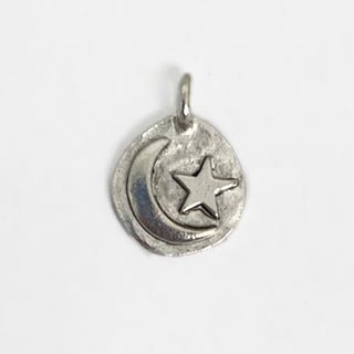 Antique Silver plated round charm with an embossed crescent moon and star on it.