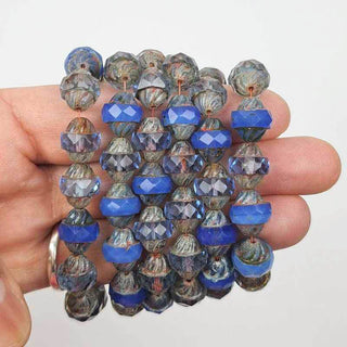 Blue faceted czech glass beads on a person's hand on a white background
