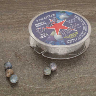 Spool of Stretch Magic Elastic Cord with beads on a textured surface