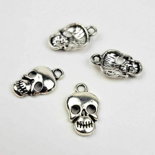 four silver tone skull charms on a white background