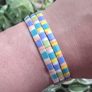 Wrist with three stretch Tila bead bracelets in spring colors.