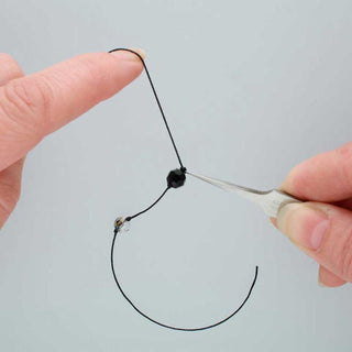Pearl Knotting Tweezers in a person's hand with beads