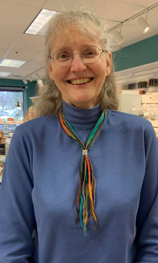 Close up of Terry wearing a necklace of multicolor silk strands.