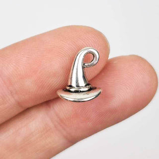 a 3D silver tone witch hat or wizard hat charm in a person's fingers