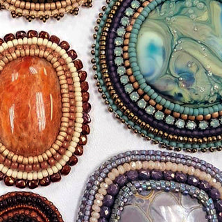 Several bead embroidered cabochons in different colorways.