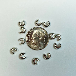 Dime for scale surrounded by silver plated bead crimps.