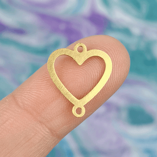 gold heart charm on finger with multicolor background