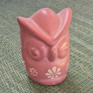 Pink owl-shaped carving on a textured green surface