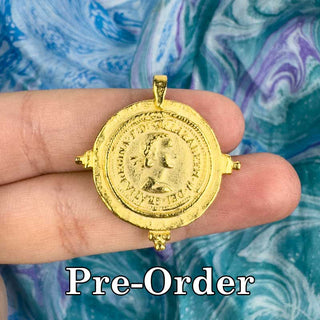 pre-order for 25mm gold coin pendant, pendant on a person's hand over a multicolor background