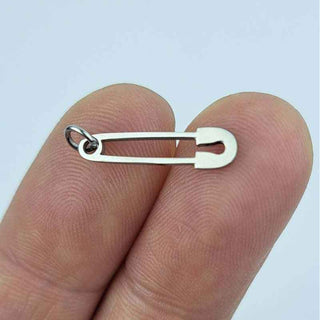 stainless steel safety pin charm on a person's fingers