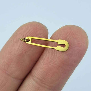 gold plated stainless steel safety pin charm on a person's fingers