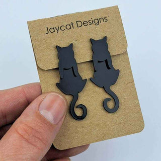 black cat earrings jacket style earrings on a brown paper jewelry card in a person's hand