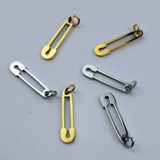 six safety pin charms in stainless steel and gold colors on a white background