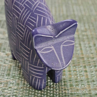Blue/Purple ceramic sculpture of a cat face on a textured green surface