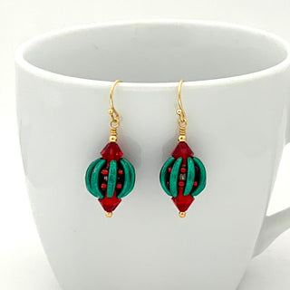 White coffee cup with red and green earrings.